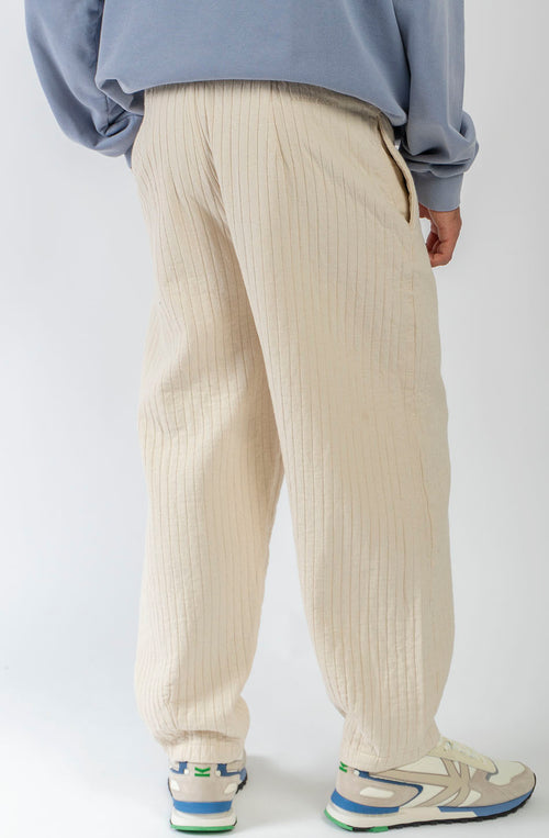 Pantalón unisex color natural con textura de rayas verticales, pierna recta y bolsillos laterales.