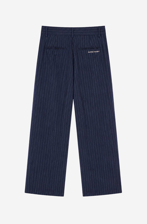Pantalón Belle Époque navy de raya diplomática blanca con pinzas delanteras, pernera ancha y detalle Kaotiko Society trasero.