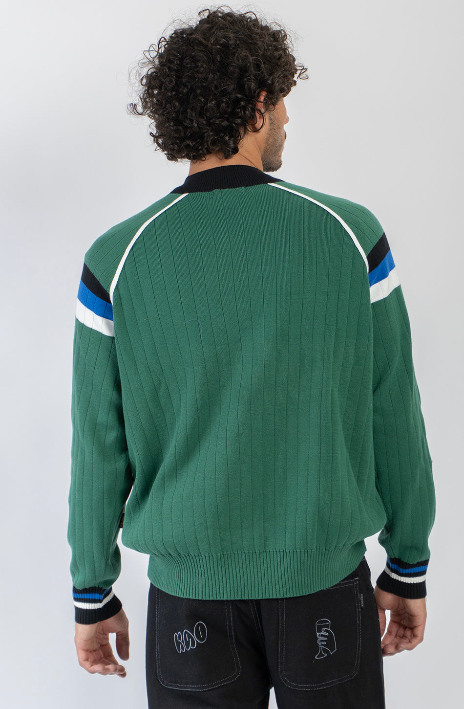 Jersey de punto verde con media cremallera, cuello alto y detalles deportivos en blanco, negro y azul.