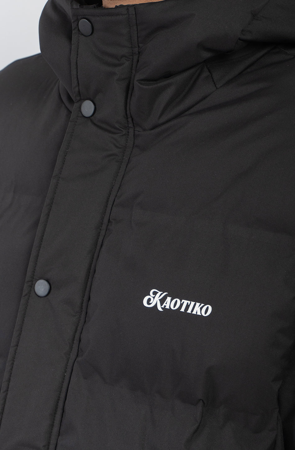 Chaqueta acolchada azul marino oscuro con capucha, cierre frontal y logo Kaotiko bordado en el pecho.
