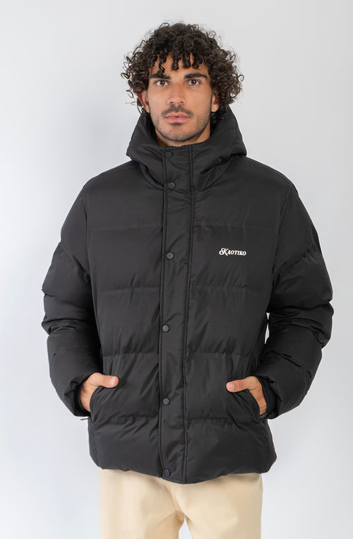 Chaqueta acolchada azul marino oscuro con capucha, cierre frontal y logo Kaotiko bordado en el pecho.