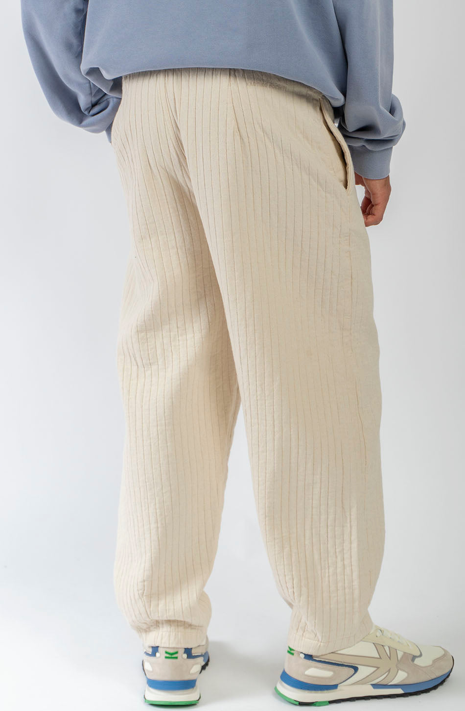 Pantalón unisex color natural con textura de rayas verticales, pierna recta y bolsillos laterales.