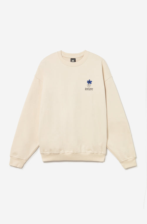 Sudadera unisex oversize color ivory con gráfico Kaotiko Society en el pecho y estampado Just Breezing en la espalda.